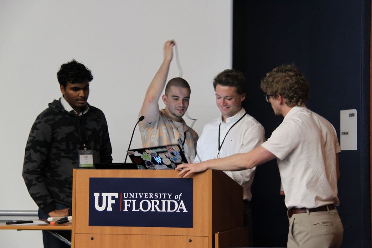 Four students at a University of Florida podium setting up a talk
