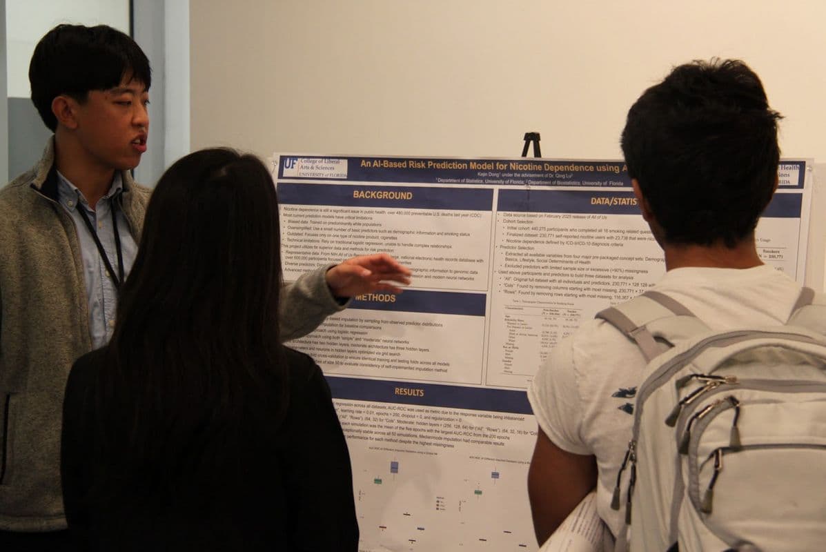 A student presenting a research poster to two attendees