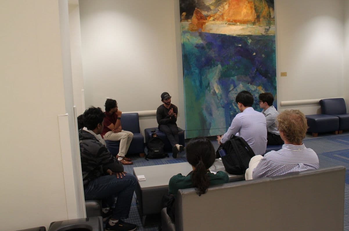 A small group in armchairs listening to a speaker