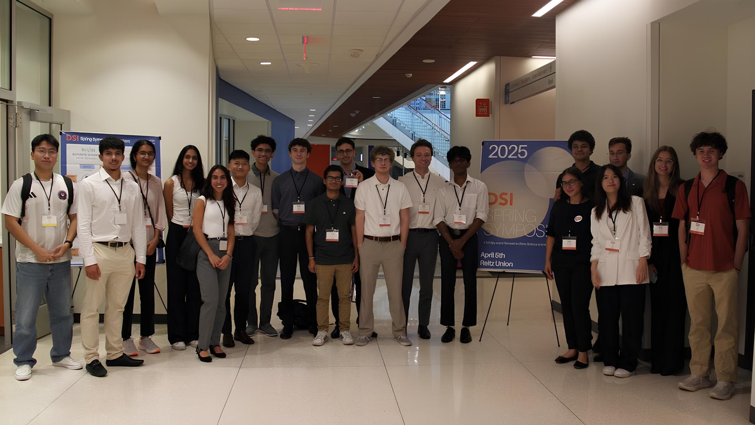 About twenty student organizers in white shirts and lanyards posing in a hallway